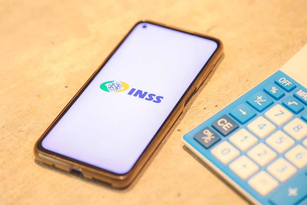 Celular com a logo do INSS e uma calculadora ao lado